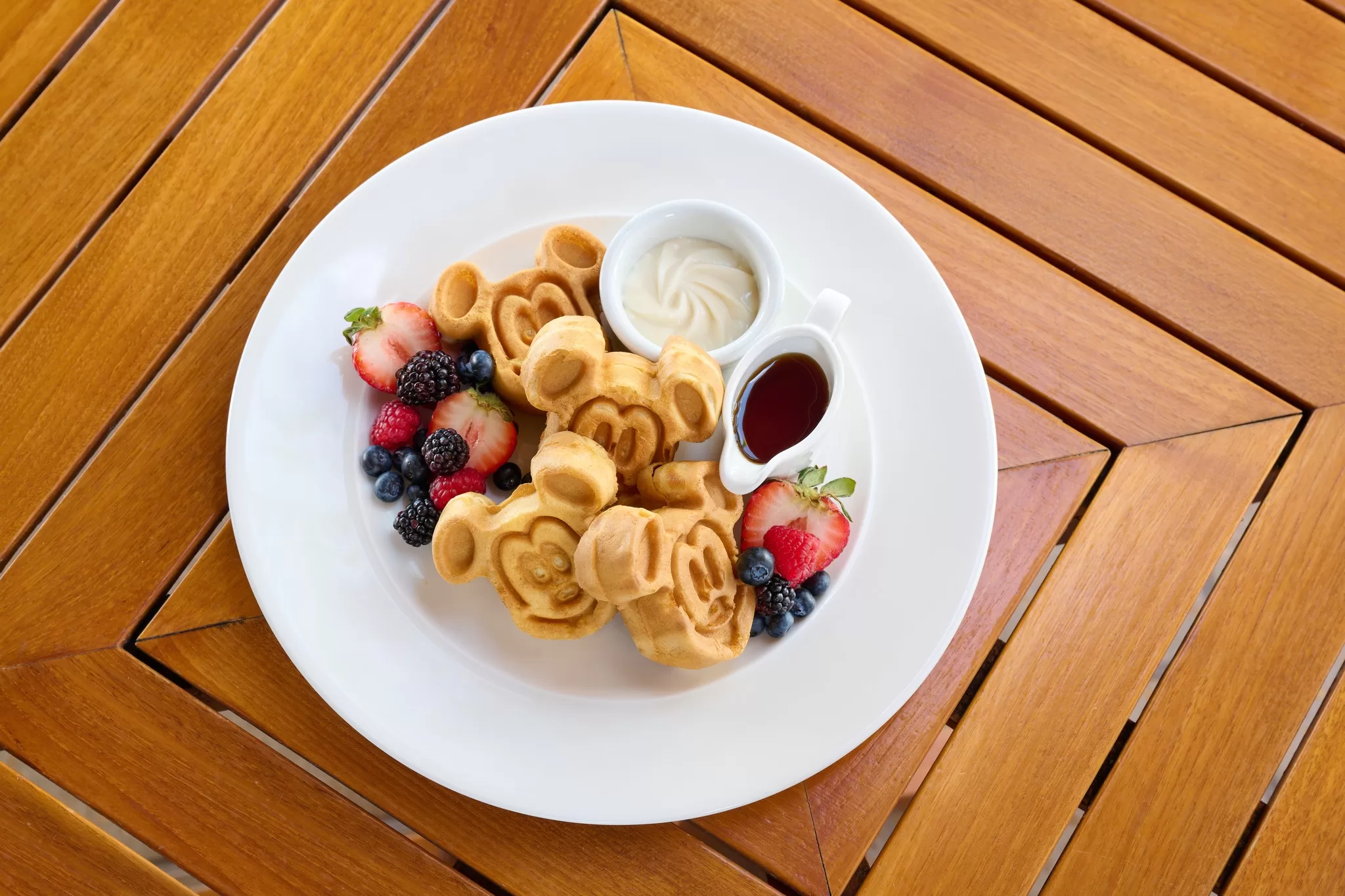 A plate with Mickey Mouse shaped waffles and fruit